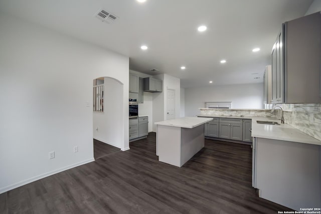 kitchen with dark wood-type flooring, sink, a center island, gray cabinets, and oven