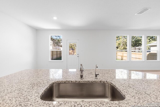 kitchen with sink, light stone countertops, and a wealth of natural light