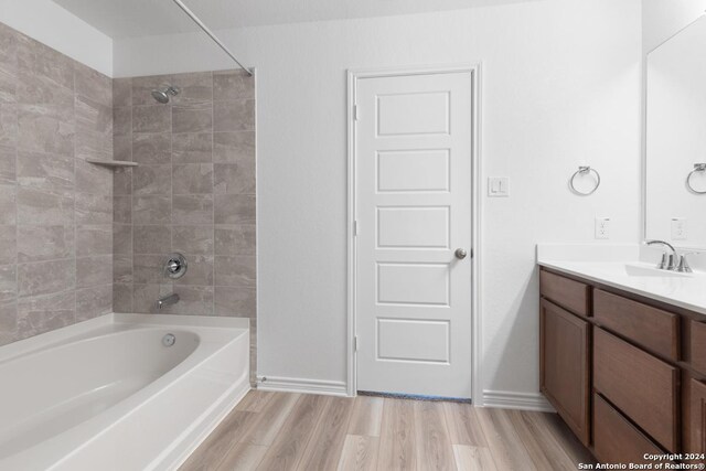 bathroom featuring hardwood / wood-style flooring, tiled shower / bath combo, and vanity