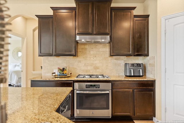 kitchen with stainless steel appliances, backsplash, light stone counters, and range hood