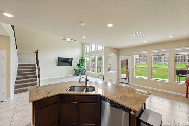 kitchen with sink, light tile patterned floors, dishwasher, a kitchen island with sink, and dark brown cabinetry