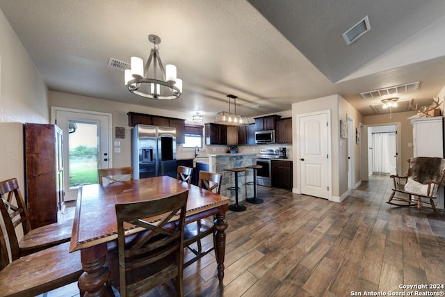 dining area with sink, an inviting chandelier, lofted ceiling, and hardwood / wood-style floors