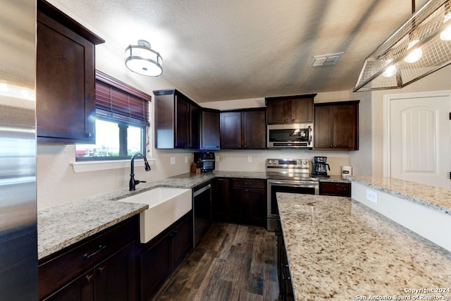 kitchen with sink, appliances with stainless steel finishes, dark wood-type flooring, and light stone counters