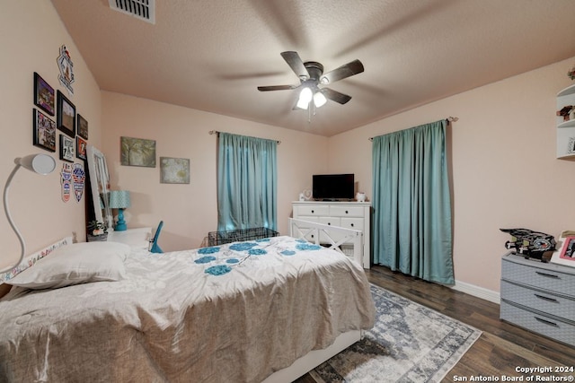 bedroom with dark hardwood / wood-style floors, ceiling fan, and a textured ceiling