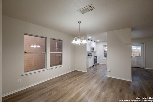 unfurnished dining area featuring a chandelier and light hardwood / wood-style flooring