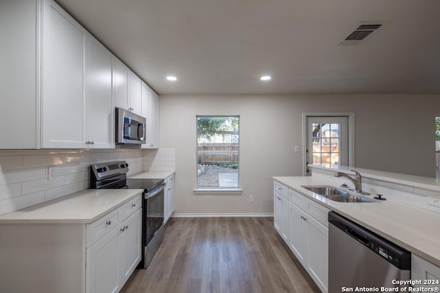 kitchen featuring sink, appliances with stainless steel finishes, a healthy amount of sunlight, decorative backsplash, and white cabinets