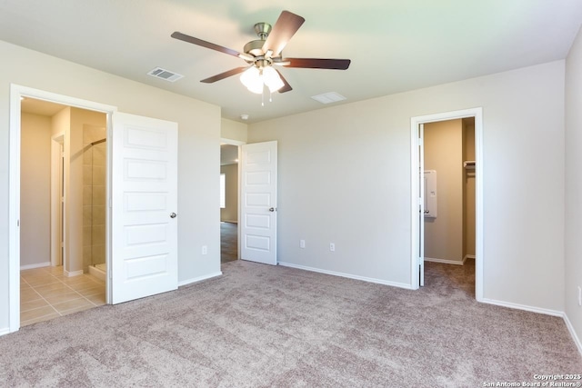 unfurnished bedroom featuring light colored carpet, connected bathroom, a spacious closet, and ceiling fan