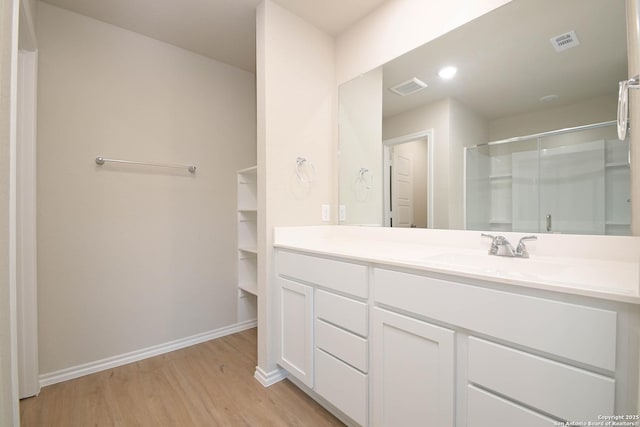 bathroom with wood-type flooring, walk in shower, and vanity