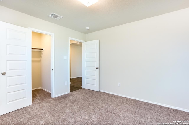 unfurnished bedroom featuring a spacious closet, light colored carpet, and a closet