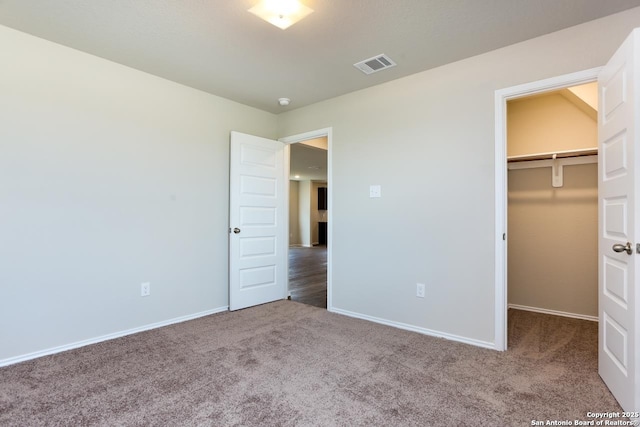 unfurnished bedroom featuring carpet floors, a closet, and a walk in closet