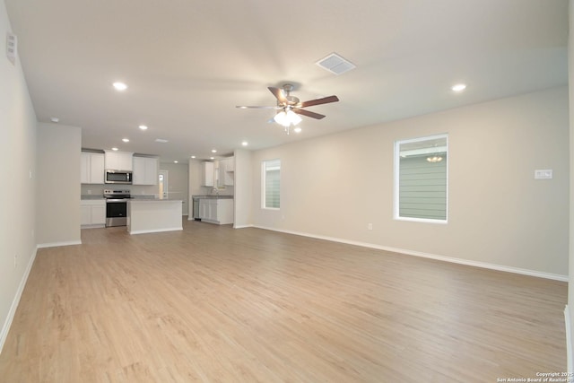 unfurnished living room featuring ceiling fan and light hardwood / wood-style floors