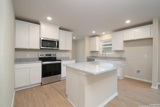 kitchen with sink, white cabinetry, light stone countertops, a kitchen island, and stainless steel appliances