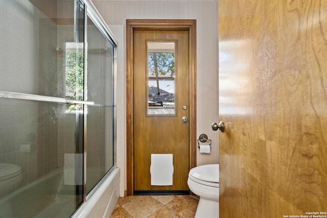 bathroom with enclosed tub / shower combo and toilet