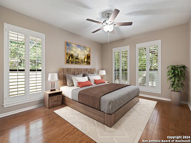 bedroom with ceiling fan, wood-type flooring, multiple windows, and a textured ceiling