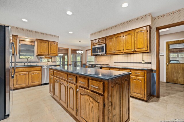 kitchen featuring sink, an inviting chandelier, stainless steel appliances, a center island, and decorative backsplash