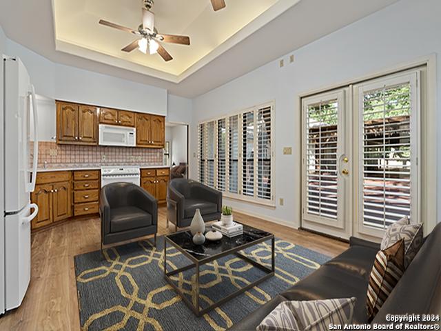 living room featuring light hardwood / wood-style floors, a raised ceiling, ceiling fan, and french doors