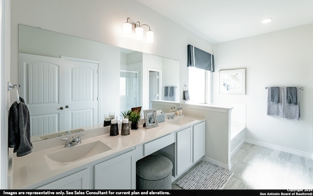 bathroom featuring double vanity, a tub to relax in, and a wealth of natural light