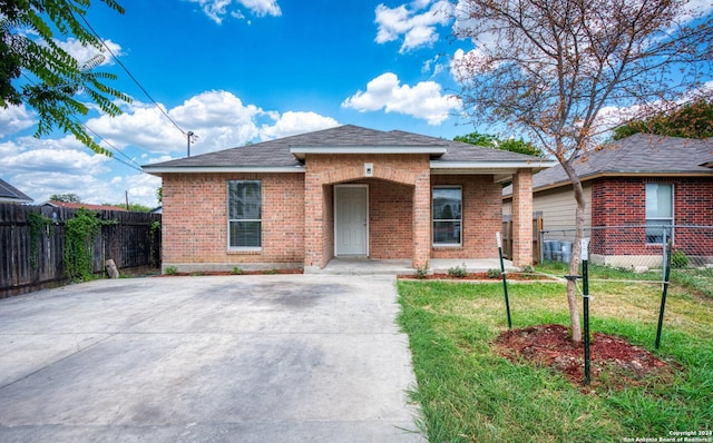 bungalow with brick siding, a front yard, and fence