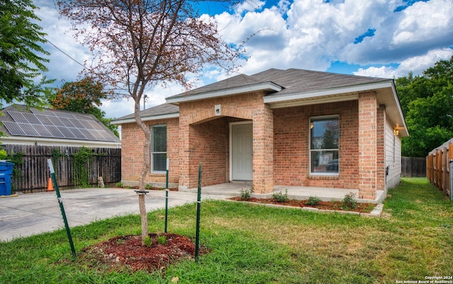 view of front of home featuring brick siding, a shingled roof, a front lawn, and fence