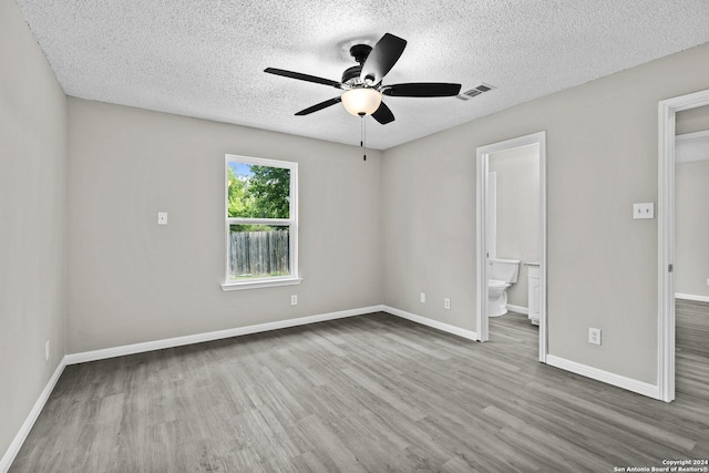 unfurnished bedroom featuring visible vents, a textured ceiling, baseboards, and wood finished floors