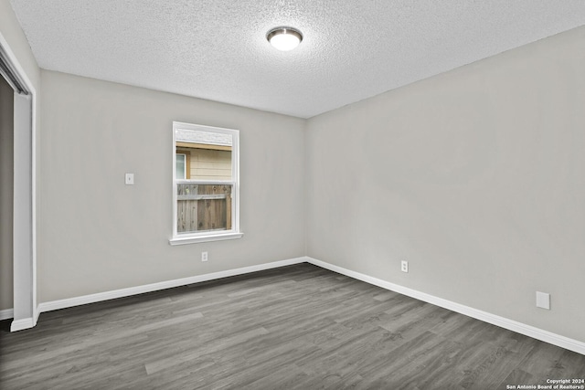 unfurnished room with a textured ceiling, baseboards, and wood finished floors