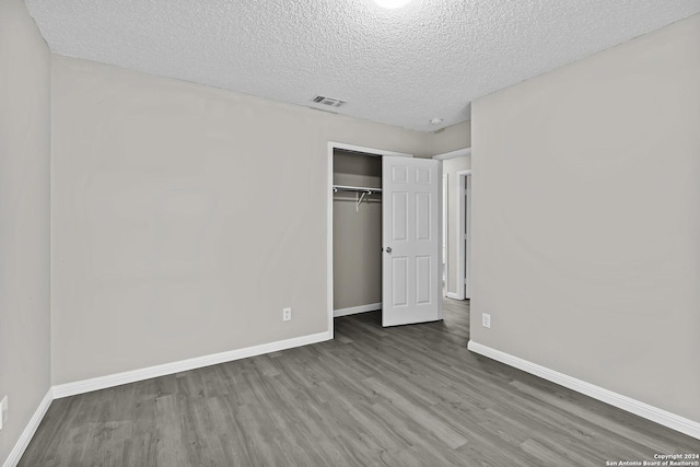 unfurnished bedroom with visible vents, baseboards, a closet, and wood finished floors