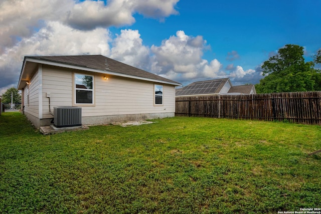 rear view of house featuring a lawn, central AC, and fence private yard