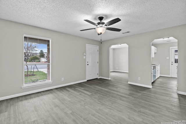 interior space with visible vents, a ceiling fan, wood finished floors, arched walkways, and baseboards