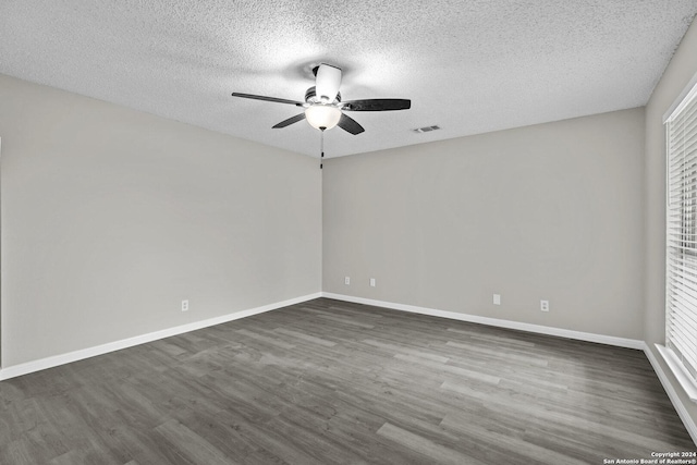 empty room featuring visible vents, baseboards, and dark wood finished floors