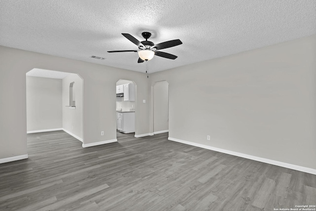 spare room featuring arched walkways, visible vents, dark wood finished floors, and baseboards