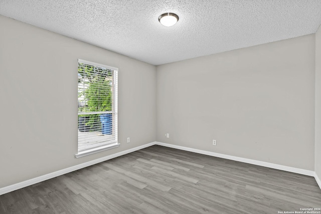 empty room featuring wood finished floors, baseboards, and a textured ceiling