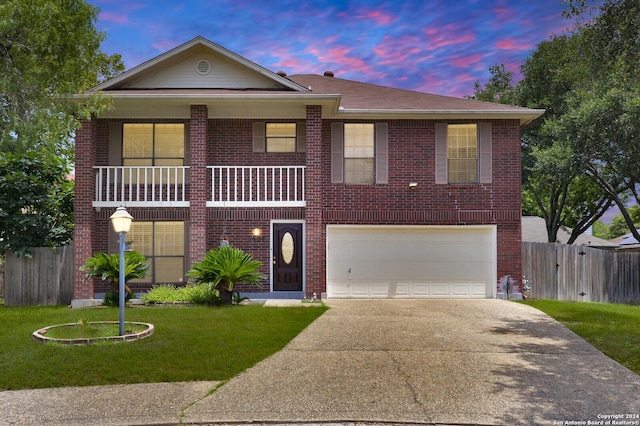 view of front of home featuring a balcony, a yard, and a garage