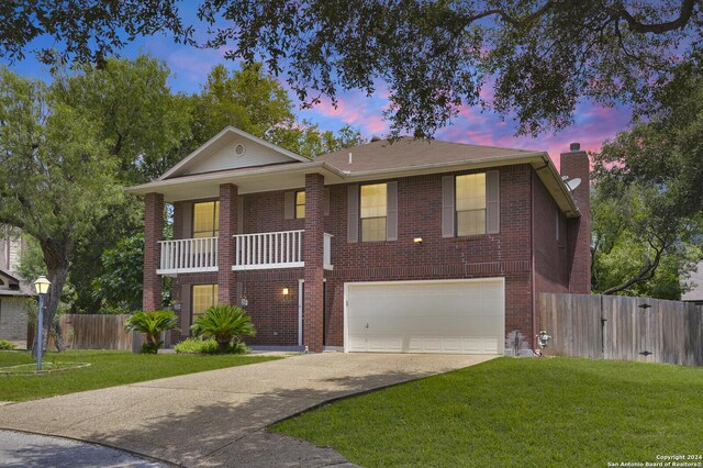 view of front facade featuring a garage, a balcony, and a yard