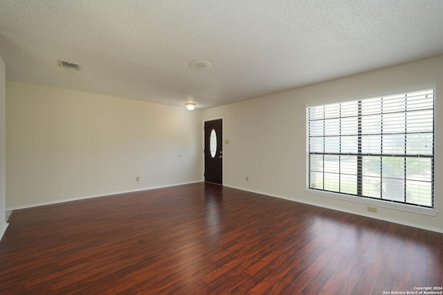 spare room featuring dark hardwood / wood-style floors and a textured ceiling