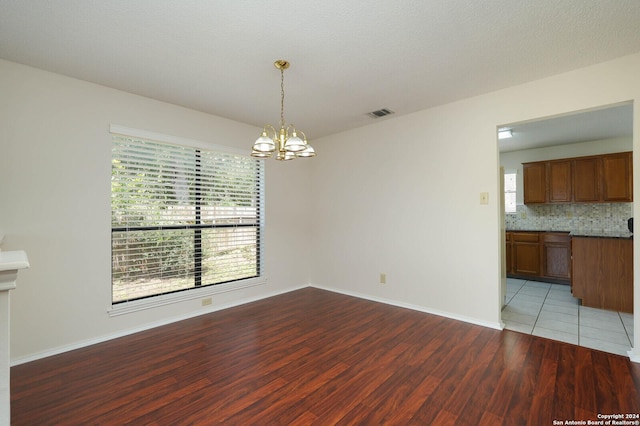 unfurnished dining area featuring an inviting chandelier and hardwood / wood-style flooring