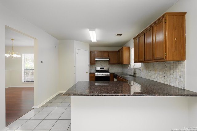 kitchen with sink, backsplash, dark stone counters, kitchen peninsula, and stainless steel range oven