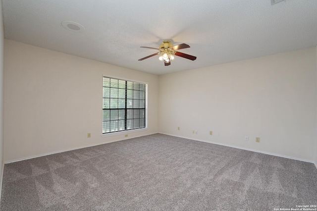 empty room featuring a textured ceiling, ceiling fan, and dark colored carpet