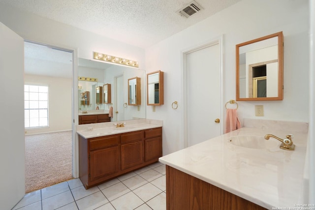 bathroom with tile patterned flooring, vanity, and a textured ceiling