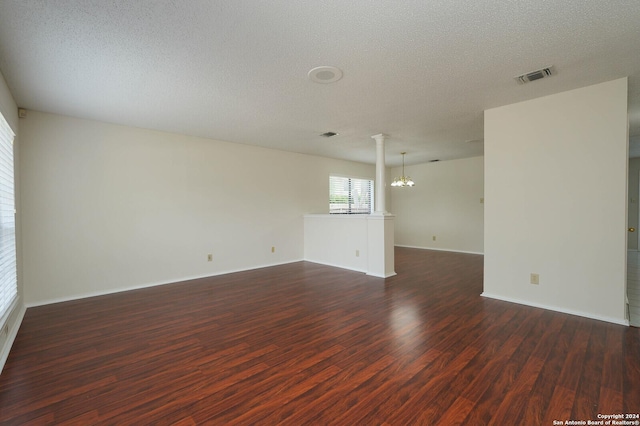 empty room with dark hardwood / wood-style flooring, a notable chandelier, and a textured ceiling