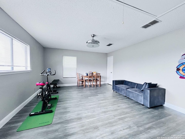 workout area featuring visible vents, a textured ceiling, baseboards, and wood finished floors