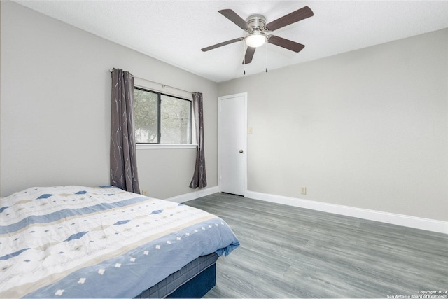 bedroom with ceiling fan, a textured ceiling, baseboards, and wood finished floors