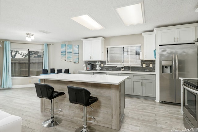 kitchen featuring appliances with stainless steel finishes, a center island, a kitchen bar, and tasteful backsplash