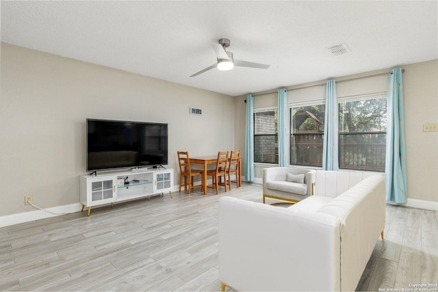 living room featuring baseboards, visible vents, ceiling fan, wood finished floors, and a textured ceiling