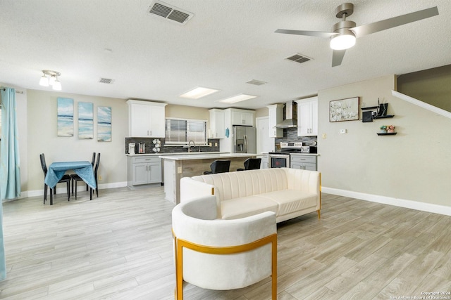 living area featuring a textured ceiling, light wood-type flooring, and visible vents