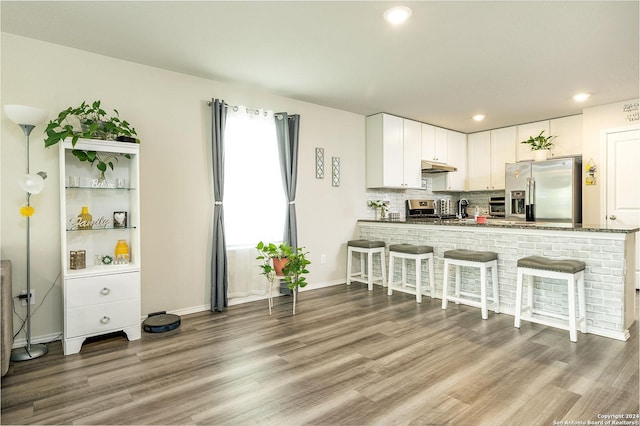 kitchen featuring white cabinetry, stainless steel appliances, kitchen peninsula, and hardwood / wood-style flooring