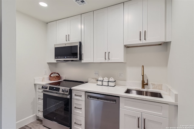 kitchen with white cabinetry, sink, stainless steel appliances, and light hardwood / wood-style floors