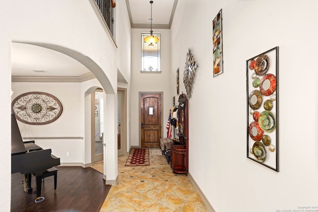 foyer entrance featuring ornamental molding, light wood-type flooring, and a high ceiling