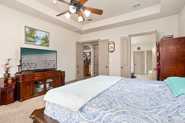 bedroom with ceiling fan, carpet flooring, and a tray ceiling