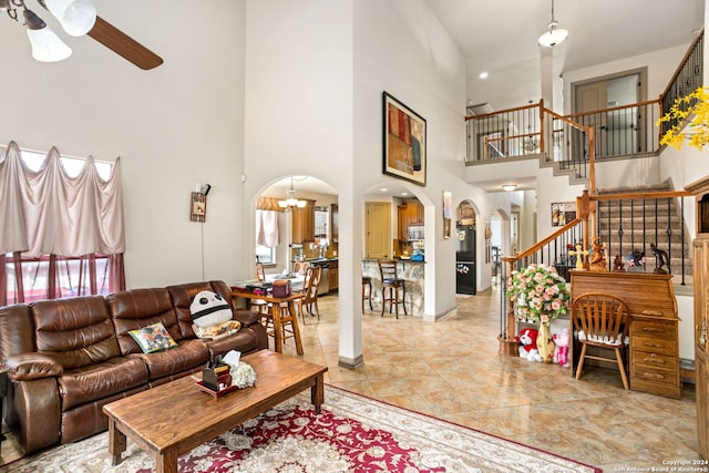 tiled living room featuring ceiling fan with notable chandelier, a high ceiling, and a healthy amount of sunlight