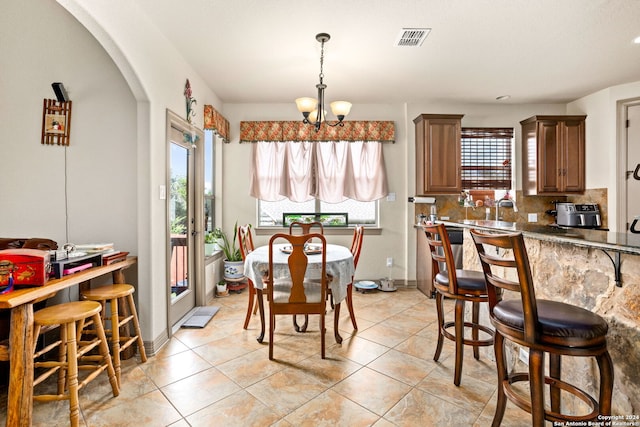 tiled dining area featuring sink and a chandelier